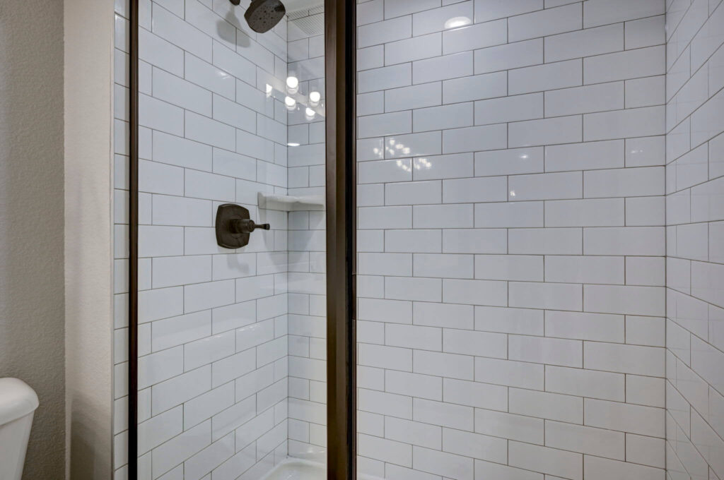 Glass-enclosed shower with white subway tile and oil-rubbed bronze fixtures.