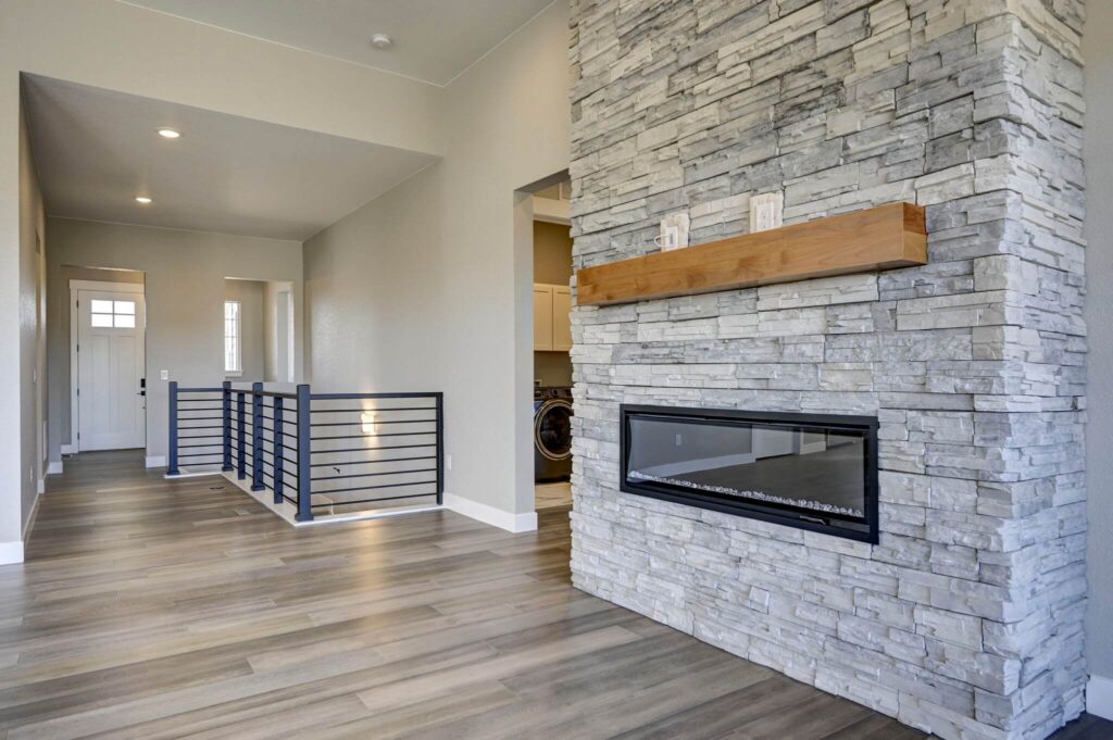 Corner view of stone fireplace and adjacent hallway with black horizontal railing.