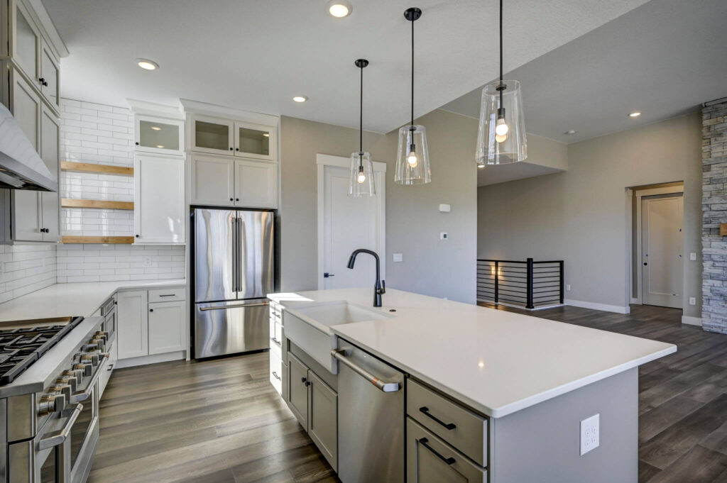 Kitchen island with farmhouse sink, dishwasher, stainless appliances and open shelving.
