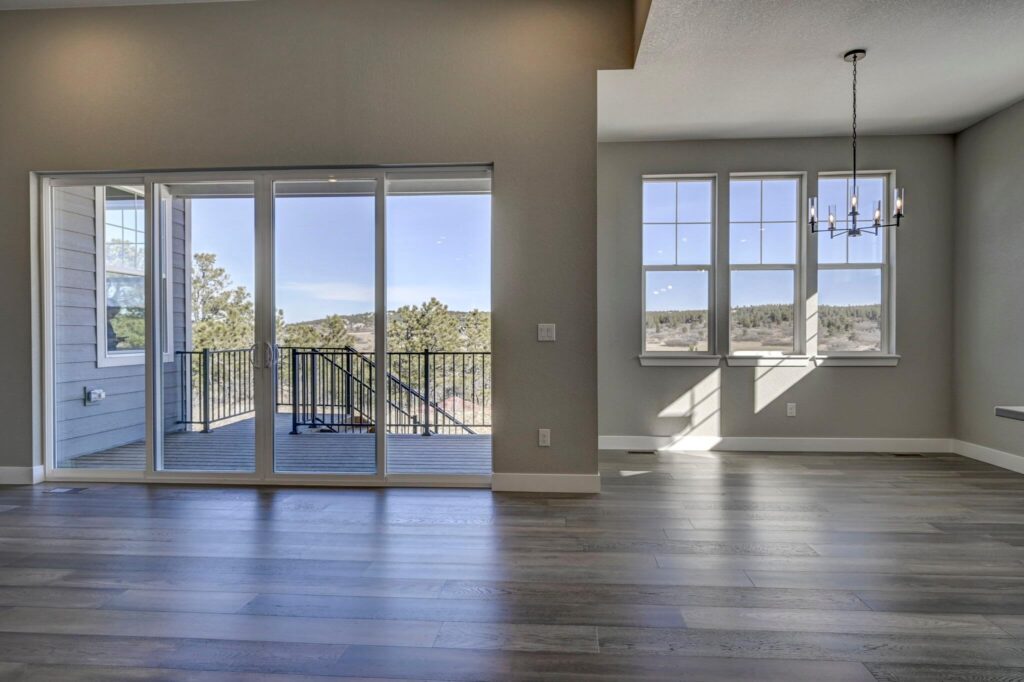Spacious room with sliding glass doors to a deck on the left and a sunny windowed nook on the right.