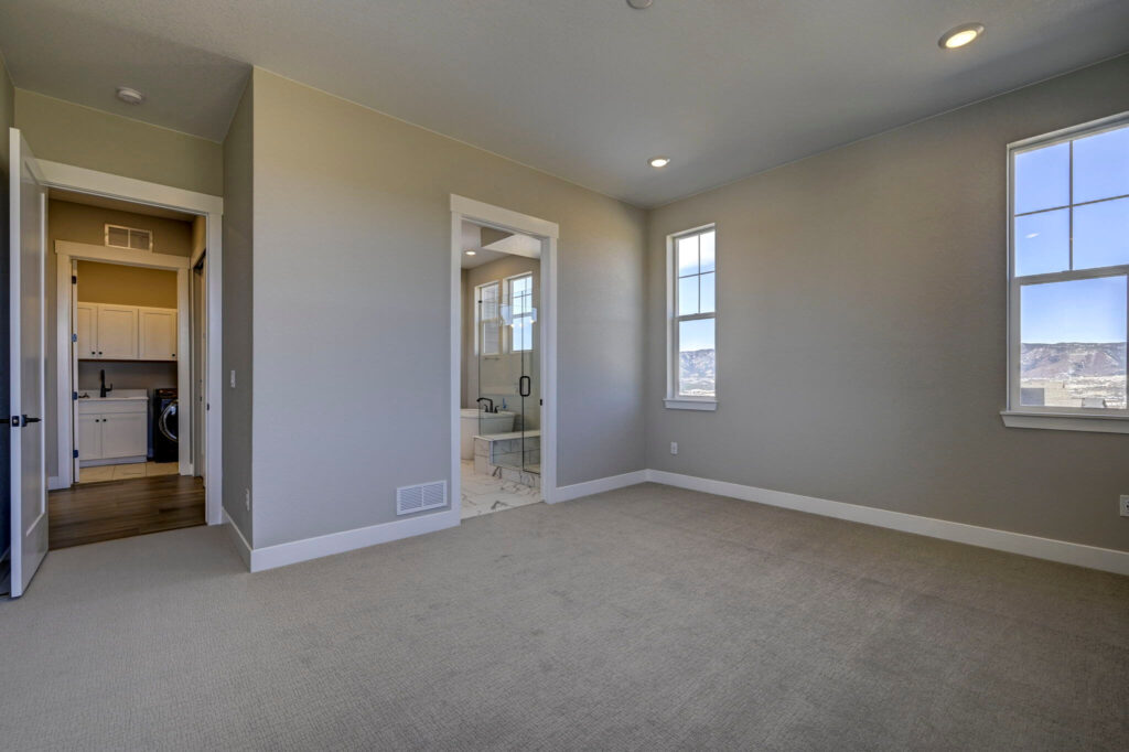 Carpeted room showing entry to hallway and an ensuite bathroom with glass shower.