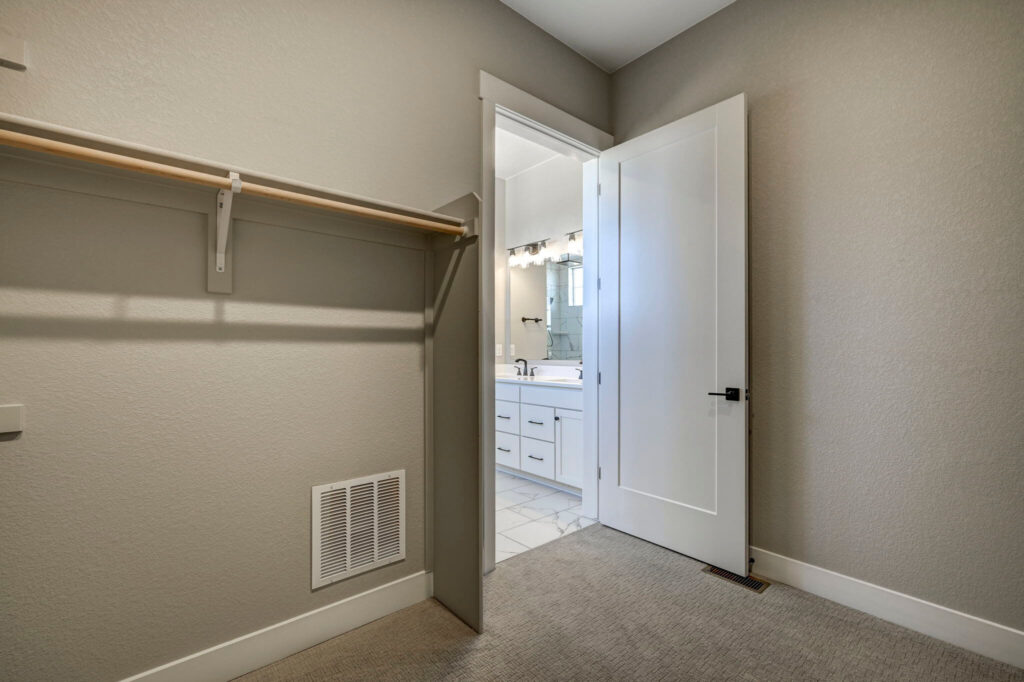 Small closet opening into a bathroom visible through a partially open white door.