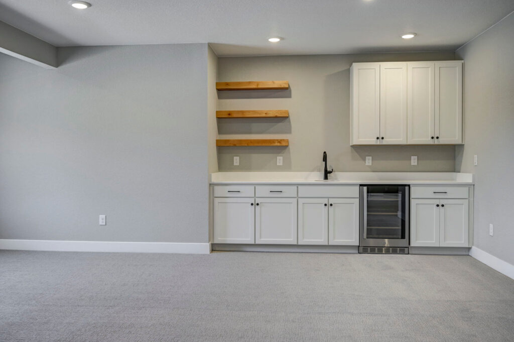 White wet bar with countertops, wood floating shelves, and a small beverage fridge