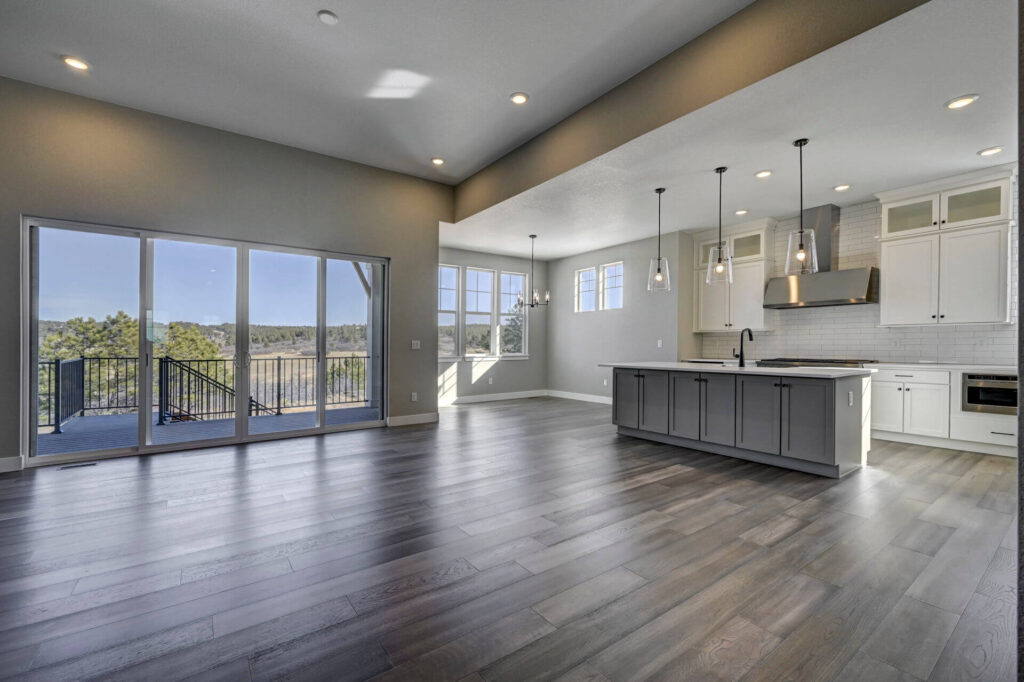 Open-plan living area with wide plank floors, kitchen island, and large sliding glass doors.
