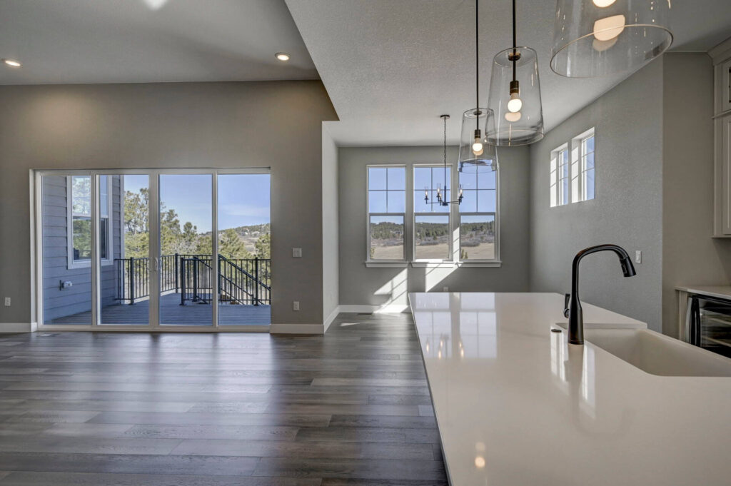 Kitchen island and dining area facing large sliding doors and windows with outdoor views.