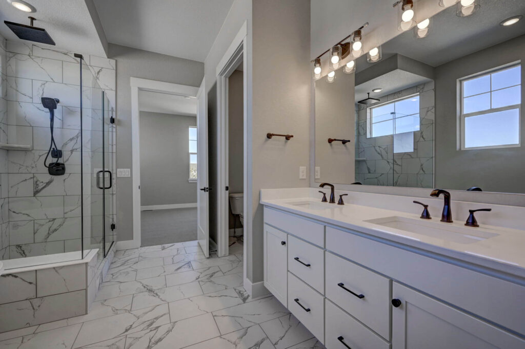 Bright bathroom with glass-enclosed shower, double-sink vanity, and marble-look floor tile.