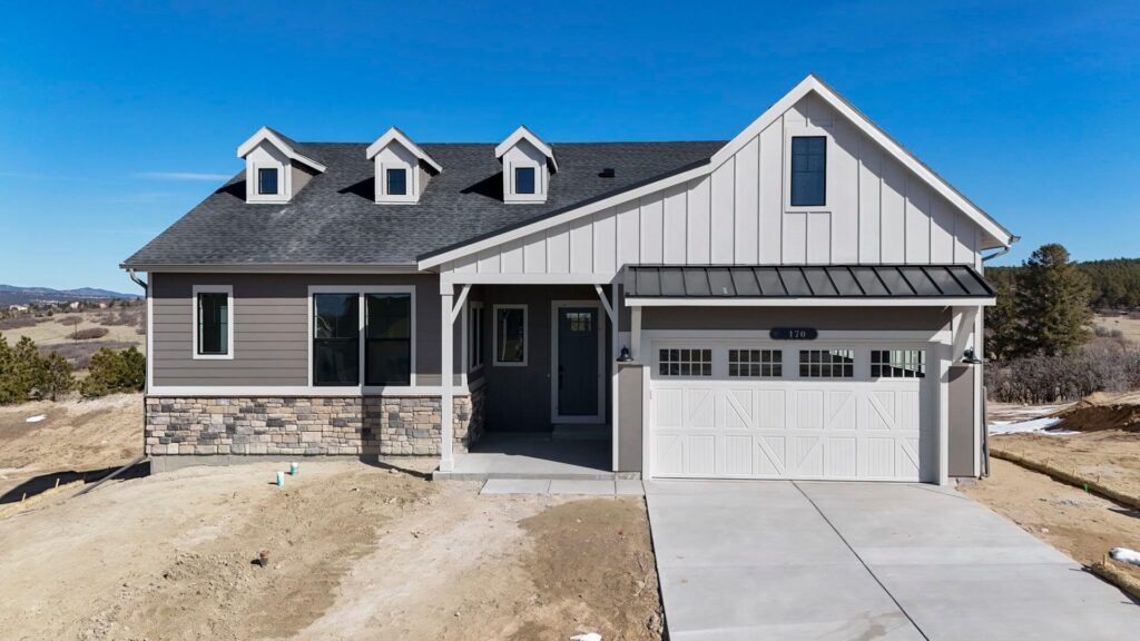 Single-story modern farmhouse-style house with three dormers and attached two-car garage.