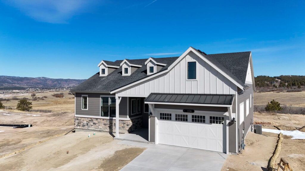 Front-right angled view of a single-story home with white garage door and prominent gable roof.
