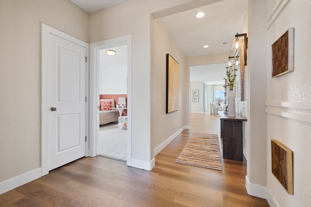 Interior entry hall with wood-look flooring, doorway to a bedroom on the left and a console table ahead.