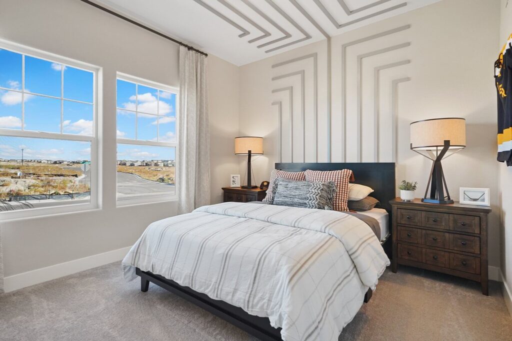 Staged bedroom with bed, patterned ceiling trim and two windows showing an exterior view.