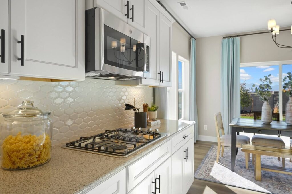 Bright kitchen counter with gas cooktop, white cabinets, microwave, and dining area beyond a window.