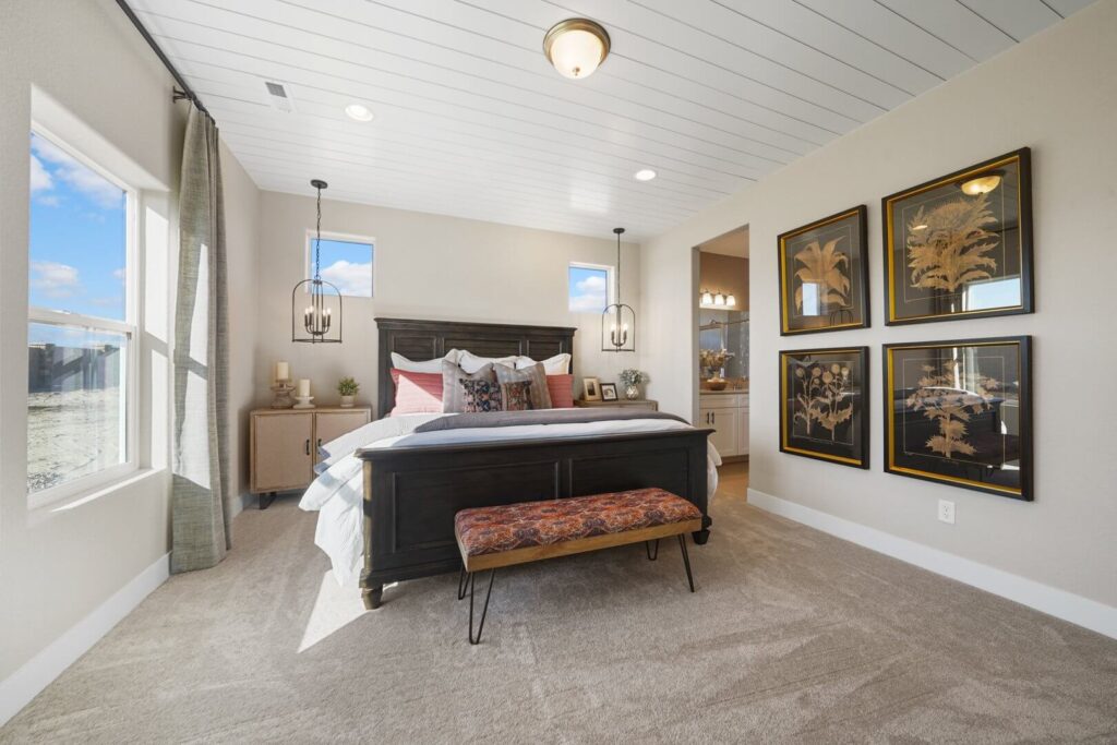 Front view of a bedroom with dark wood bed, patterned bench, hanging pendant lights, and framed wall art.