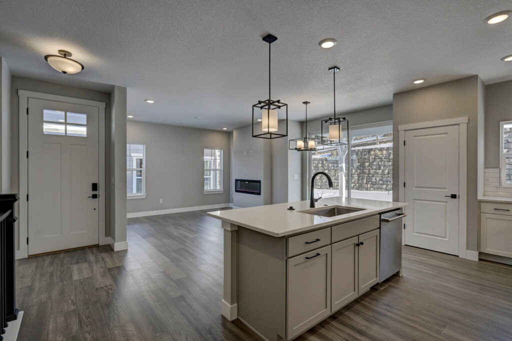 Entrance and open kitchen with island, pendant lamps, and front door visible
