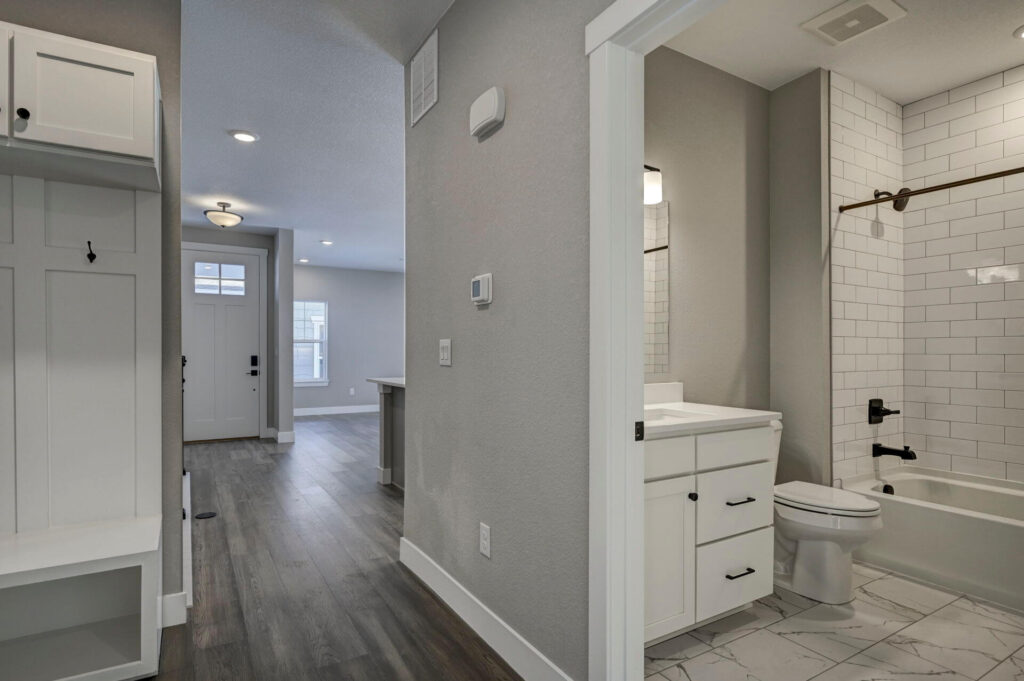 View down a hallway toward the front door with a bathroom entrance on the right.