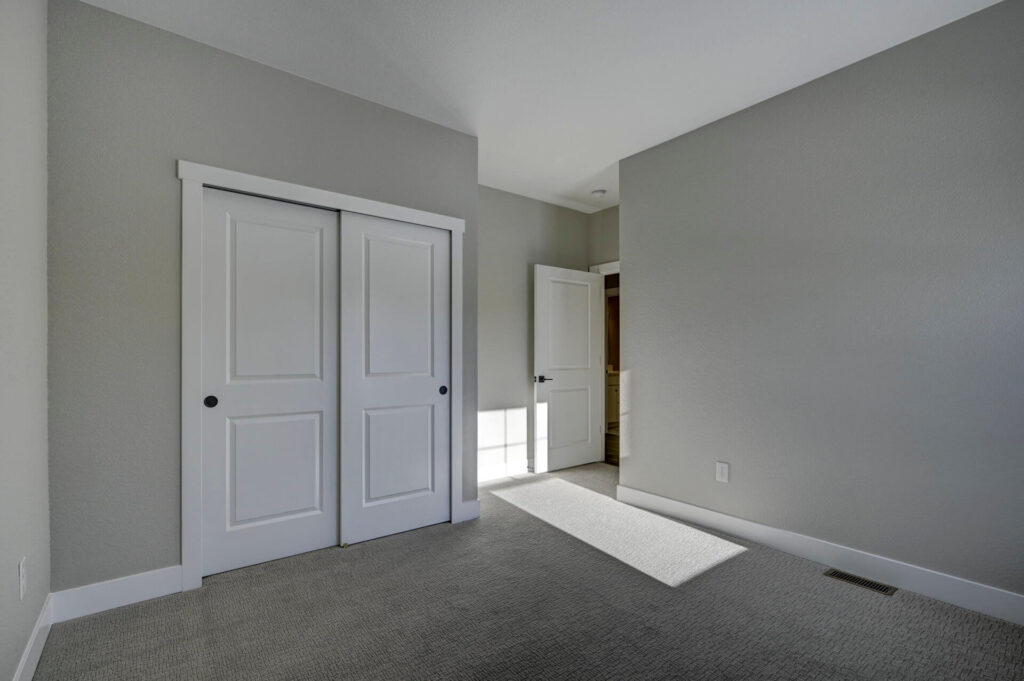 Empty room showing closet with sliding double doors and an open entry door letting in sunlight.