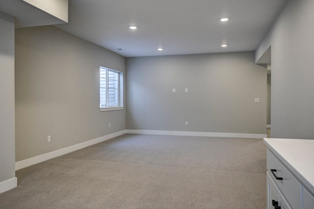 Finished basement or lower-level rec room with recessed lights and a small egress window.