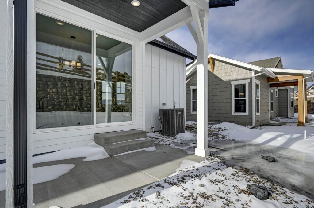 Rear covered patio area with large sliding glass door, small concrete steps, and HVAC unit.