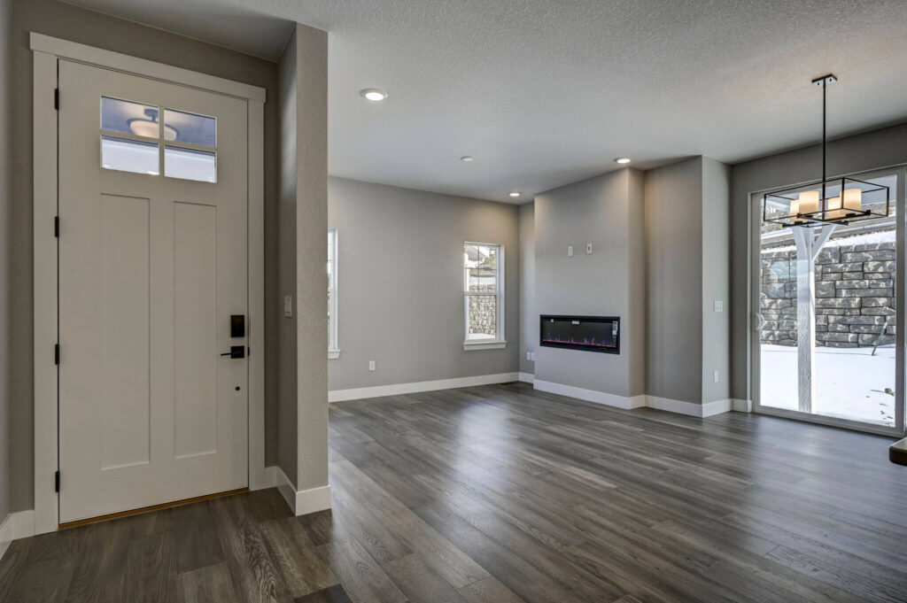 Interior view of an entry and living area with modern fireplace and sliding glass door to snowy backyard.