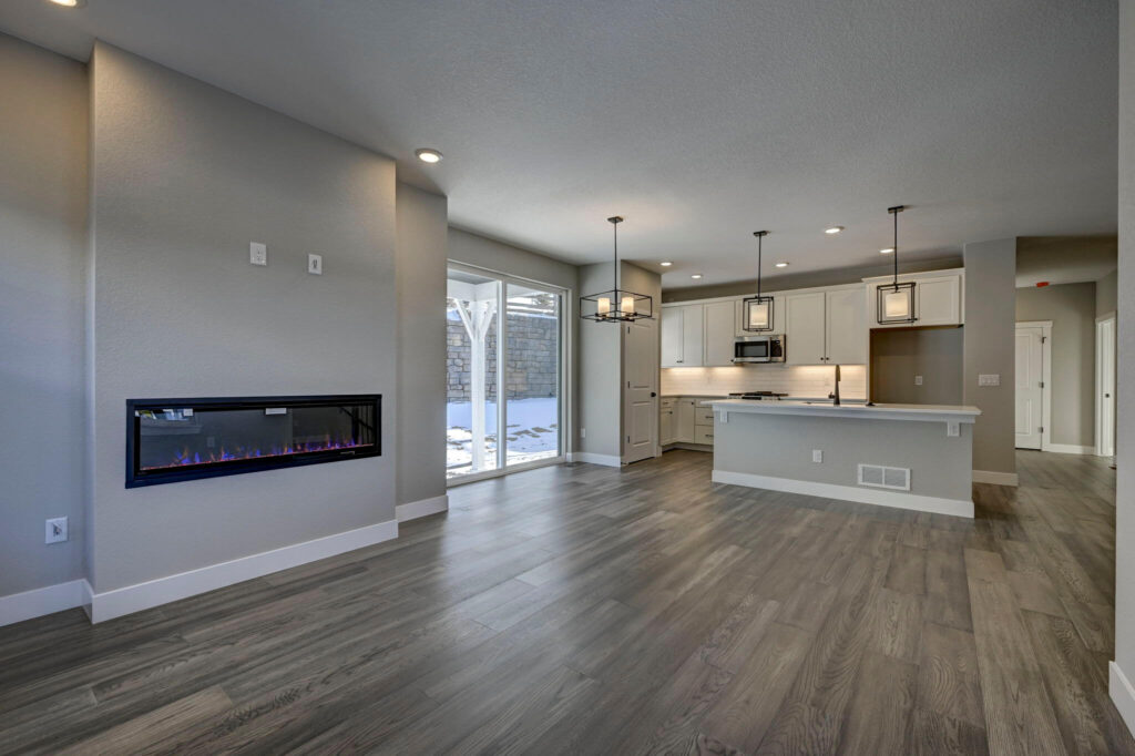 Living area with linear electric fireplace and kitchen visible through large sliding doors.