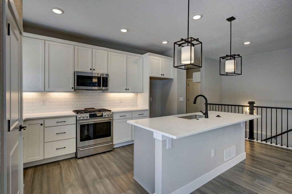 Modern kitchen with white cabinets, subway tile backsplash, stainless range, and center island.