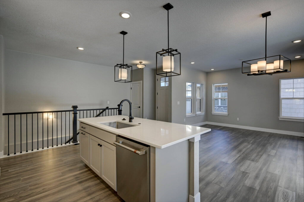 Open-concept living area seen from the kitchen island with pendant lights and railing.