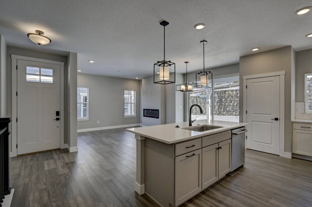 Open-plan entry, kitchen island, and living room with recessed lights and wood-look flooring.