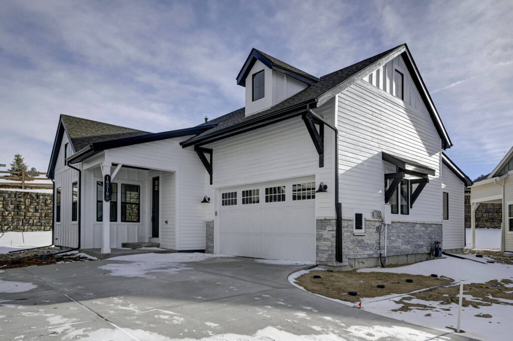 Exterior three-quarter view of a white modern farmhouse with gabled roof and attached two-car garage.