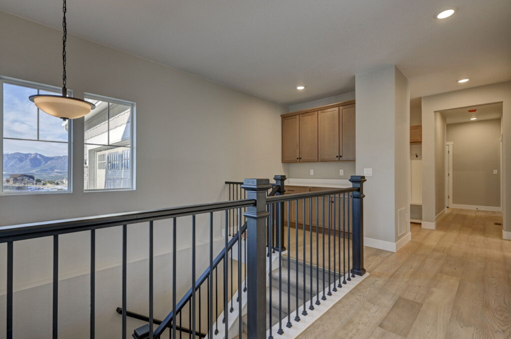 Interior landing with stair railing, built-in cabinets, and a window overlooking distant hills.