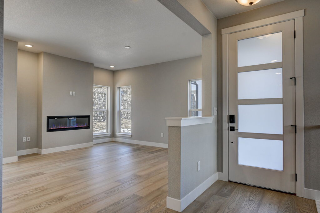 Entry and open living area with frosted-panel front door and built-in linear fireplace.