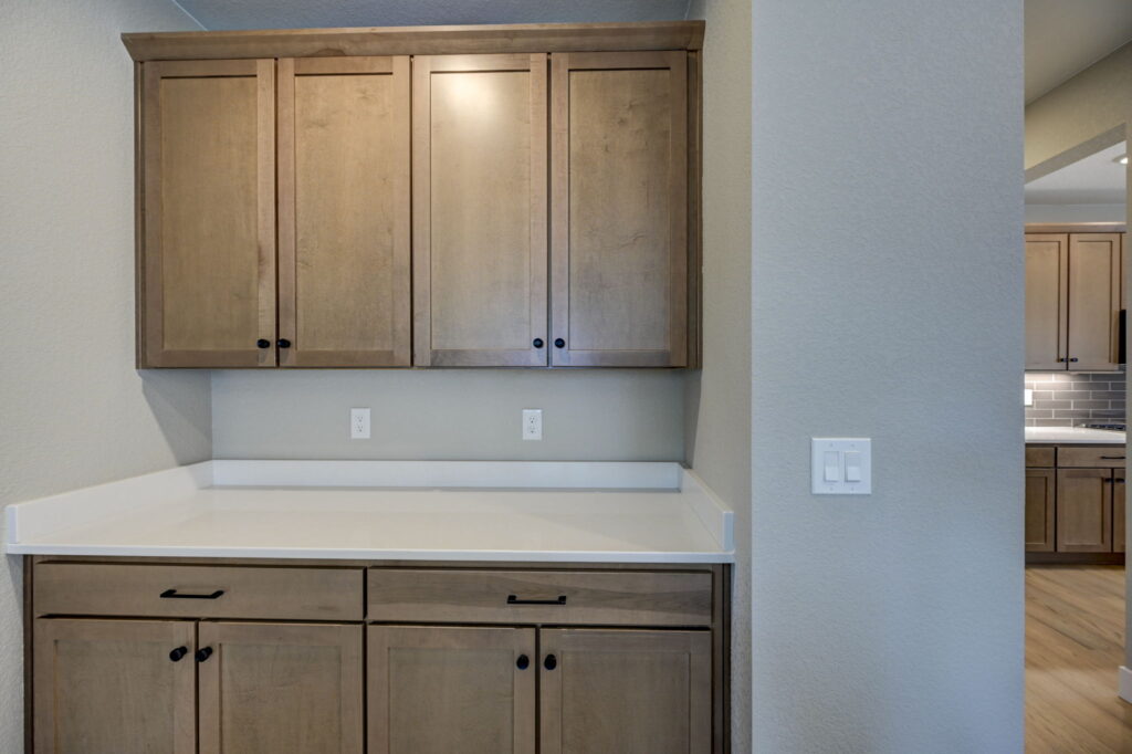 Built-in countertop and upper and lower wooden cabinets with simple hardware.