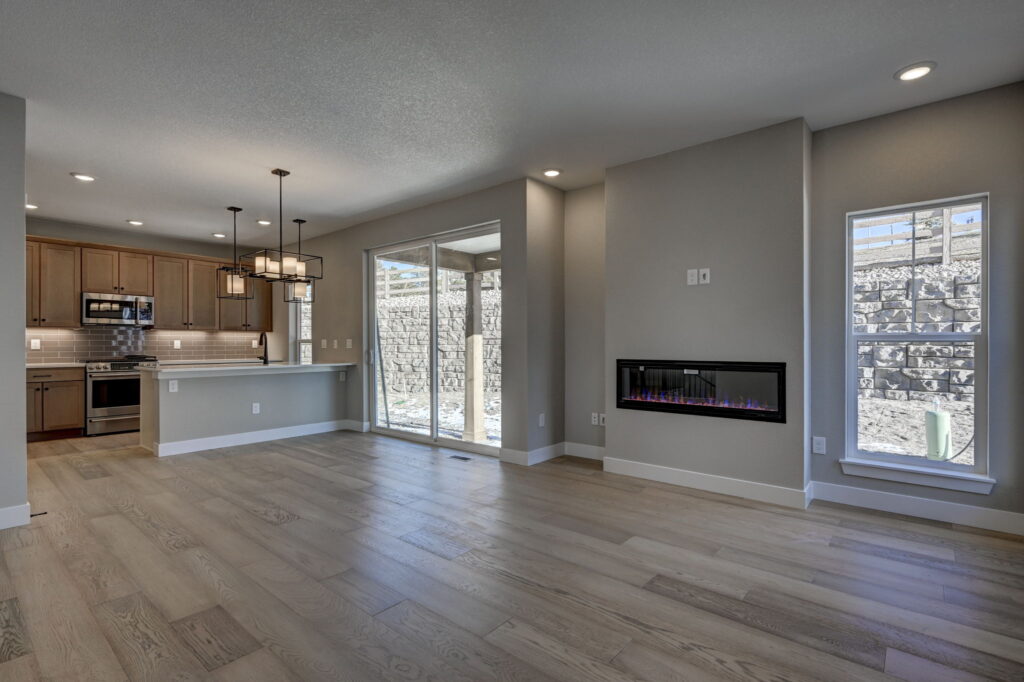 Open-plan living room and kitchen with sliding glass doors, electric fireplace, and stainless steel appliances.