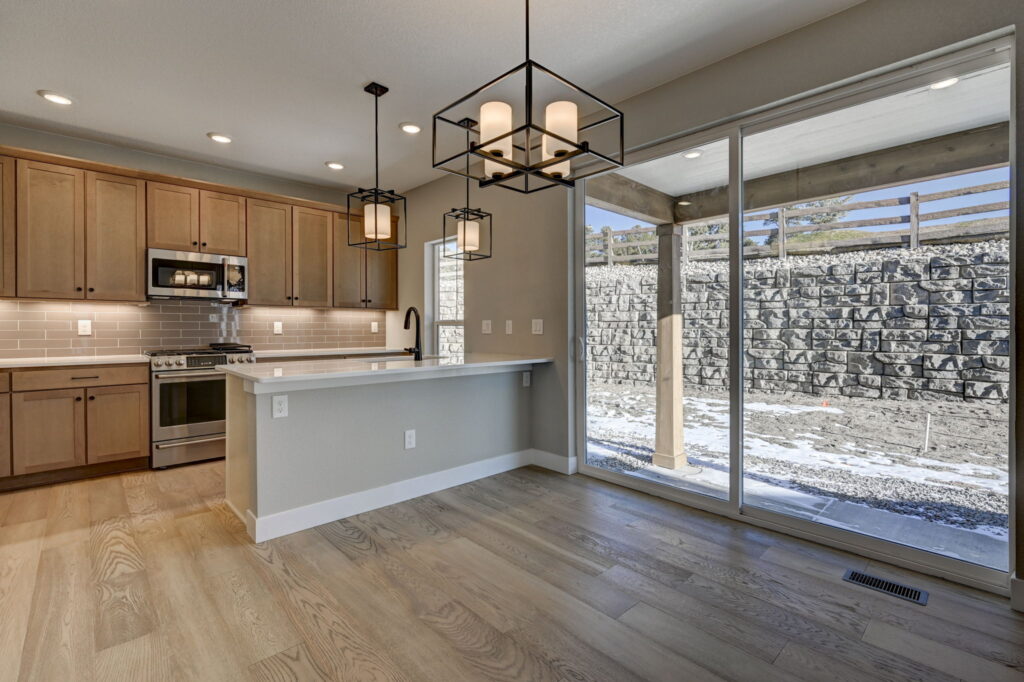 Open kitchen and dining area with island, pendant lights, sliding glass door and wood cabinetry.