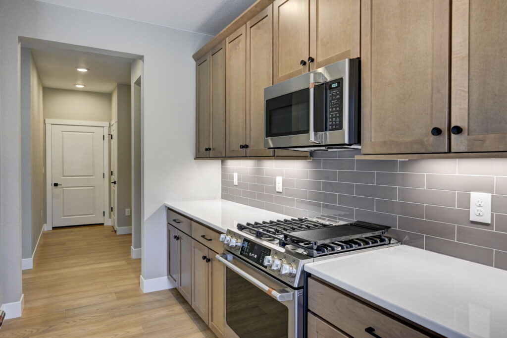 Kitchen counter with gas range, microwave and gray subway tile backsplash.
