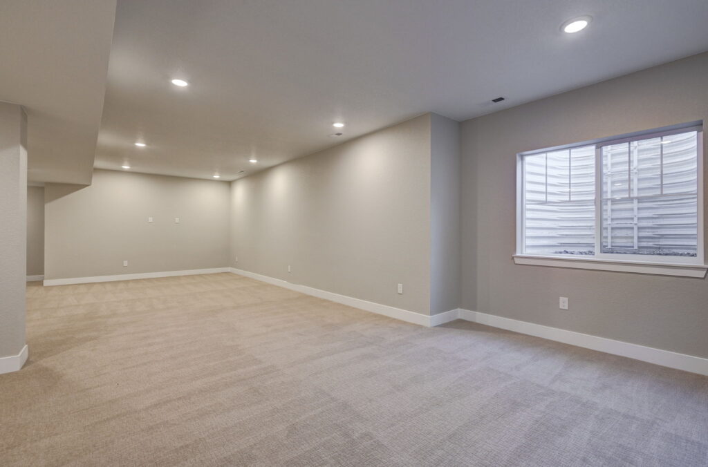 Large finished basement room with recessed lights and a window well at right.