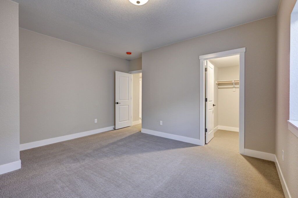Neutral-toned room with an open closet, doorway, and window on the right.