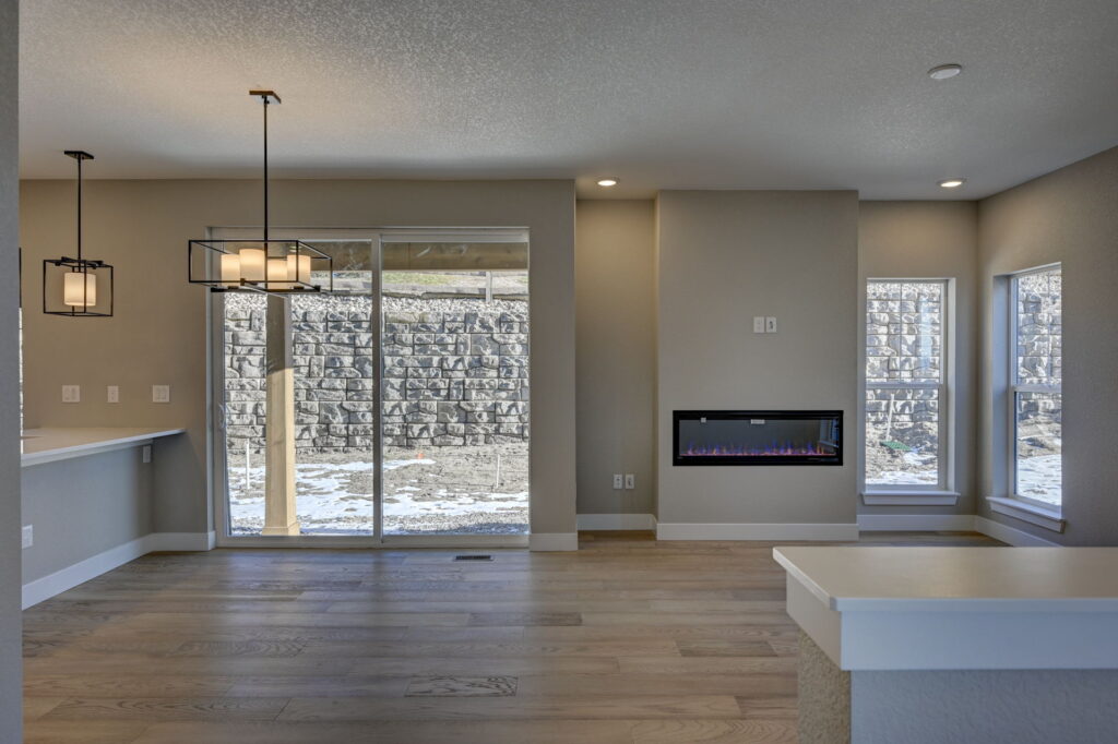Open living area with sliding glass door, wall-mounted electric fireplace, and hardwood floors.