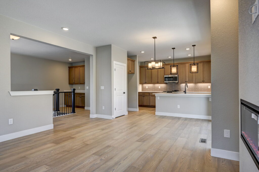 Kitchen and dining area with island, pendant lights, and pale wood cabinetry in an open floor plan.