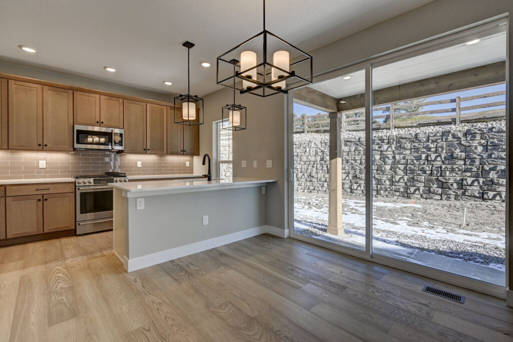 Open kitchen and dining area with island, pendant lights, sliding glass door to outside.