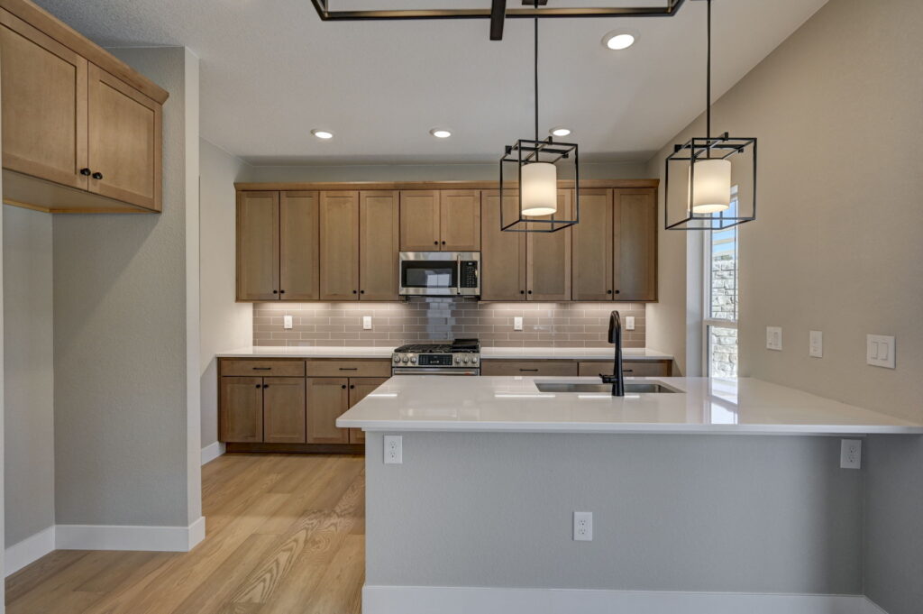 Kitchen viewed from dining area showing island with sink, pendant lights, and cabinetry.