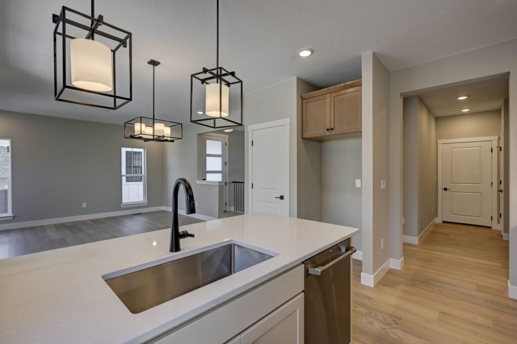 Kitchen island and sink in open-plan space with three geometric pendant lights.