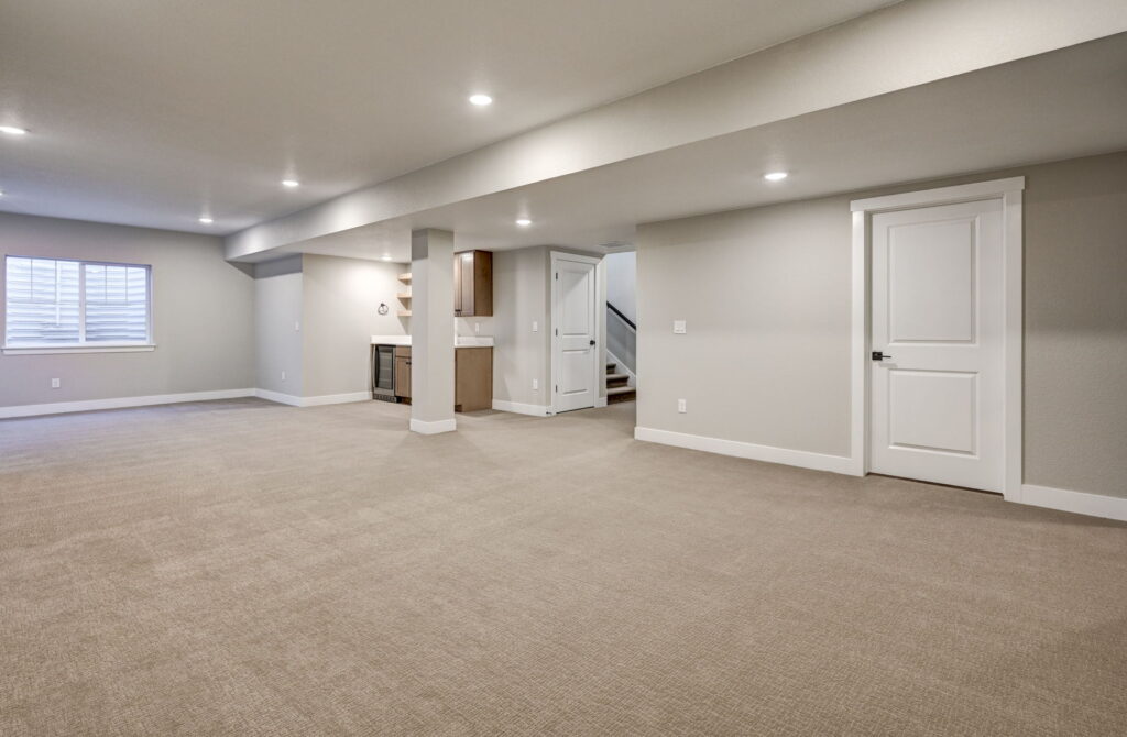 Large finished basement room with recessed lights, support column, and small wet bar area.
