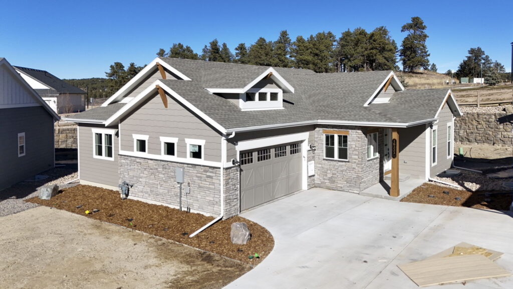 Angled exterior view of a modern ranch-style house with gabled roof and stone accents