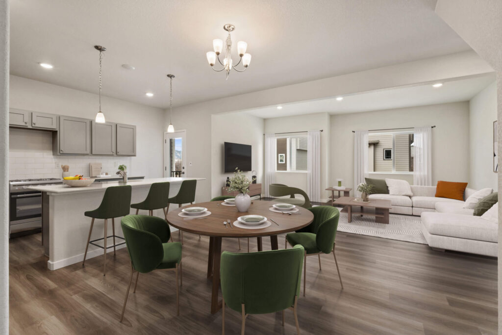 Open-plan kitchen and dining area with a round dining table and green upholstered chairs.