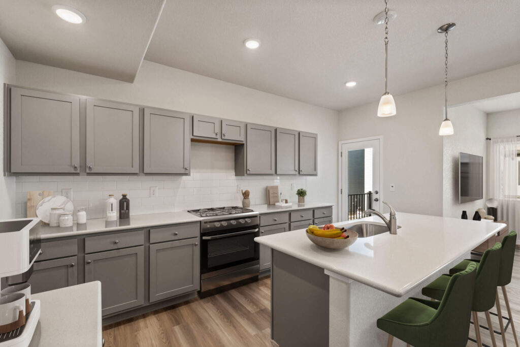 Modern kitchen with gray cabinetry, white countertops, island, and green bar stools.