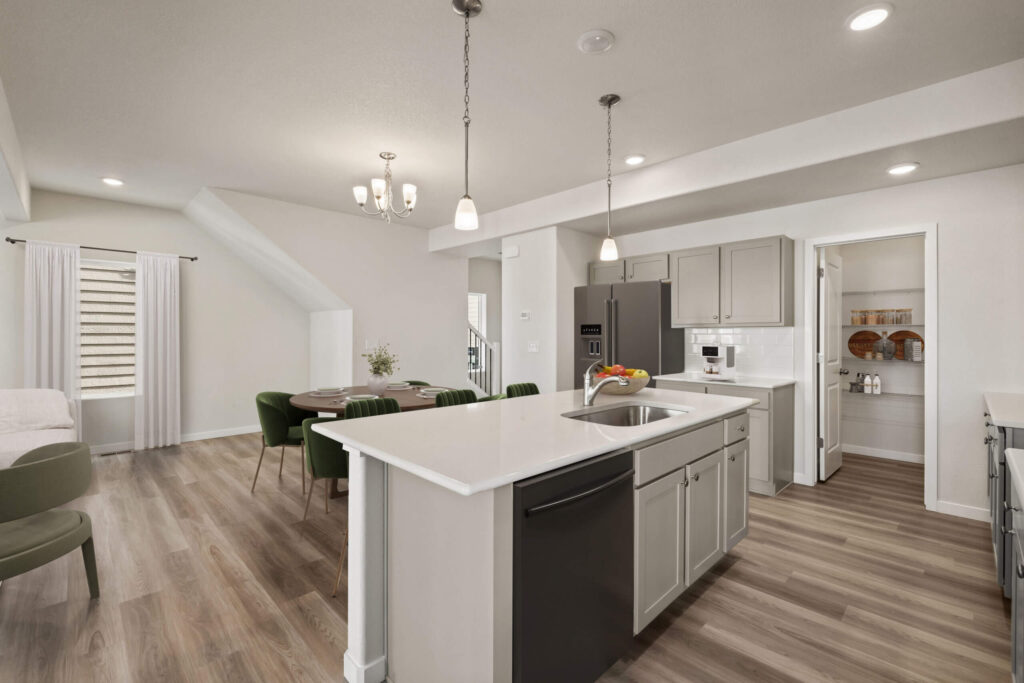 Open-plan kitchen and dining area with island, refrigerator, and dining table in background.