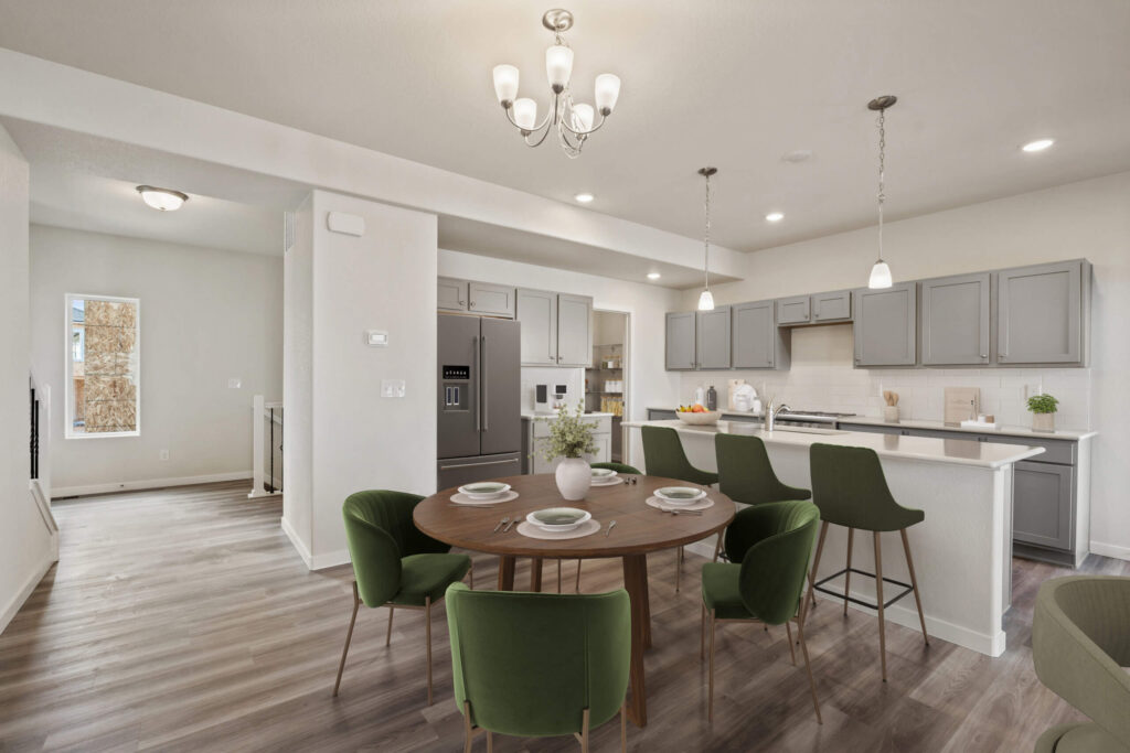 Kitchen and dining area with round table, green chairs, and breakfast bar with stools.