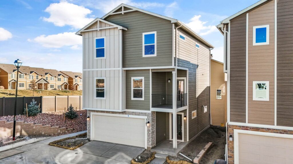 Three-story townhouse with attached two-car garage and small covered balcony above entry.