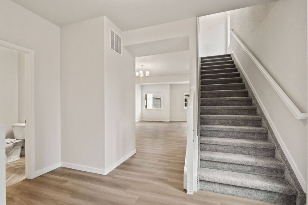 Entryway looking toward a stairway with carpeted steps and open living area beyond.