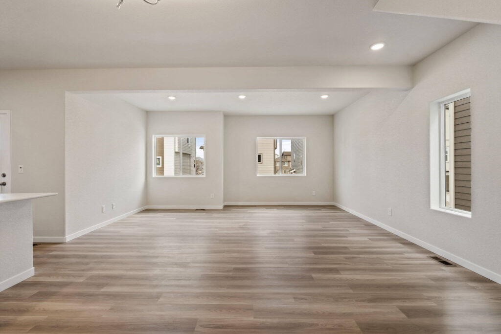 Empty rectangular living room with two windows and recessed ceiling lights.