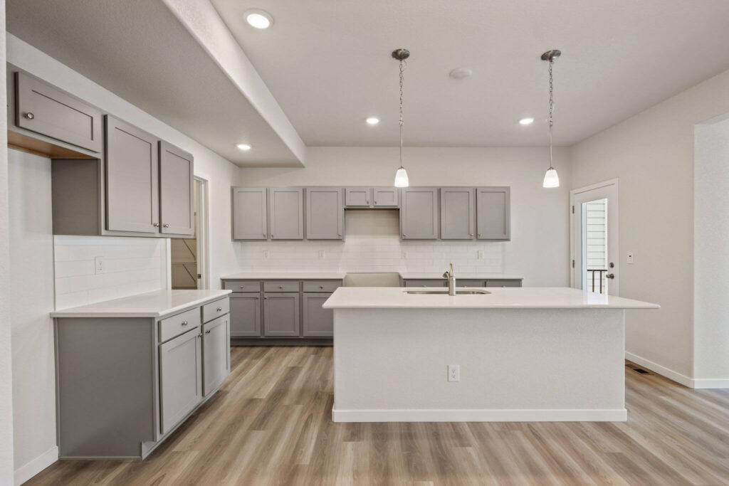 Front-facing view of a kitchen island with gray cabinets, white counters, and pendant lights.